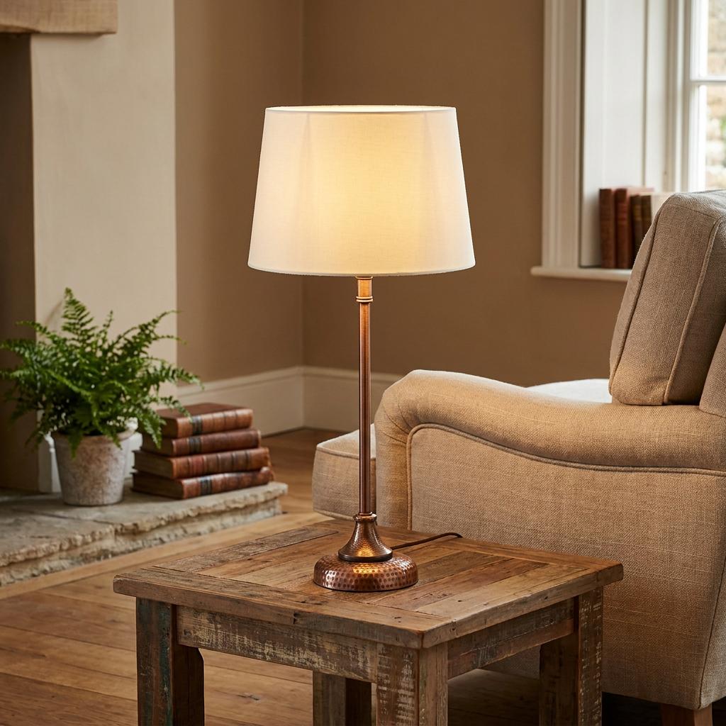 Oaks Lighting Pune Copper Table Lamp with a hammered base and white fabric shade on a rustic wooden side table.