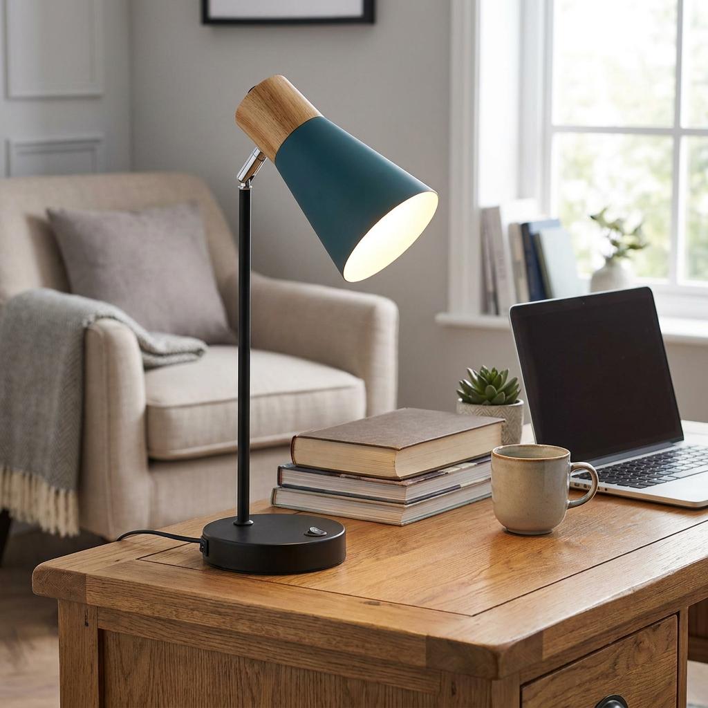 Teal and wood desk lamp illuminated on a wooden table next to books and a laptop in a cozy home office setting.