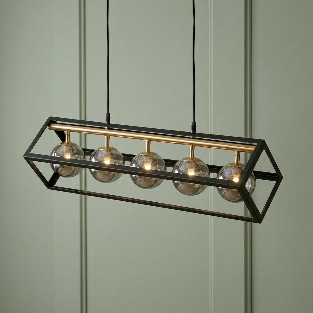 Five glass globe bulbs hanging from a gold bar inside a black rectangular frame against a green paneled wall.