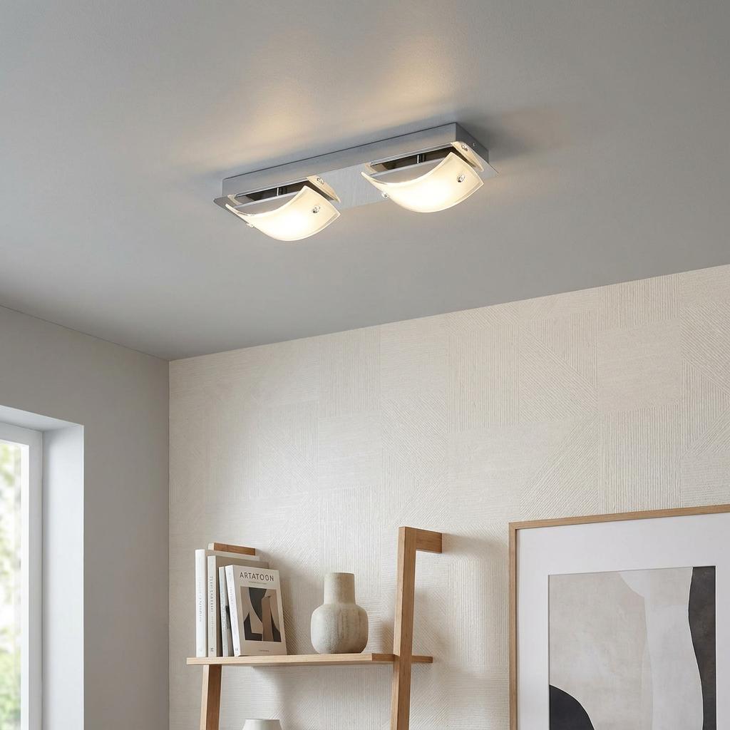 Modern two-light chrome ceiling fixture with curved frosted glass shades, illuminated in a living space.