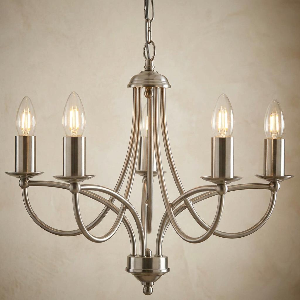 Oaks Loop Antique Chrome 5 Light Chandelier with looped arms and candle-style bulbs against a textured wall.