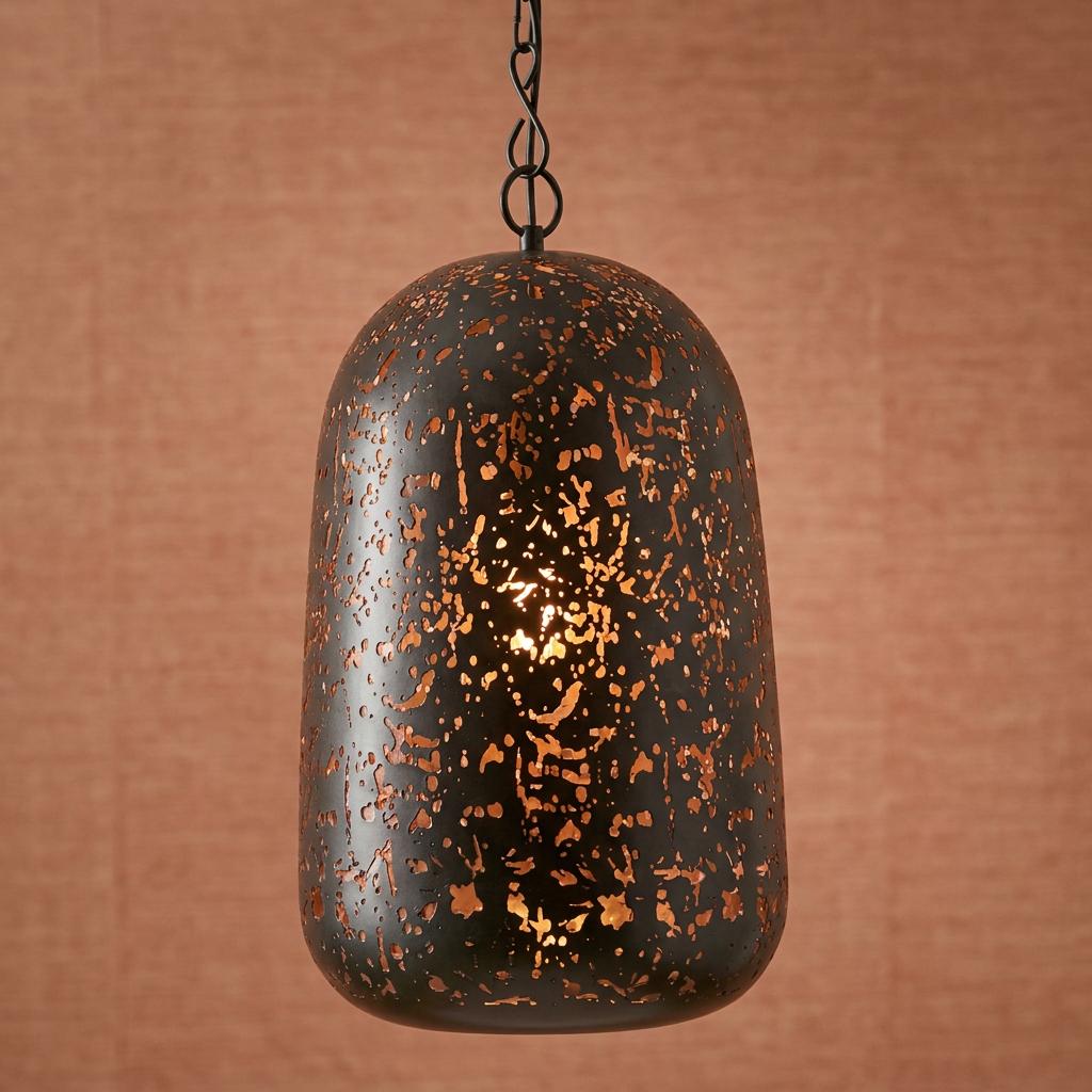 Black and copper domed pendant light with perforated cutouts hanging against a textured tan wall.