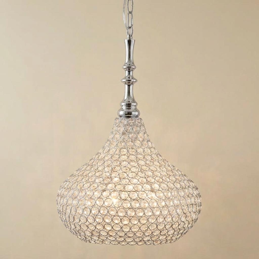 Chrome pendant light with a crystal-beaded teardrop shade glowing against a neutral background.