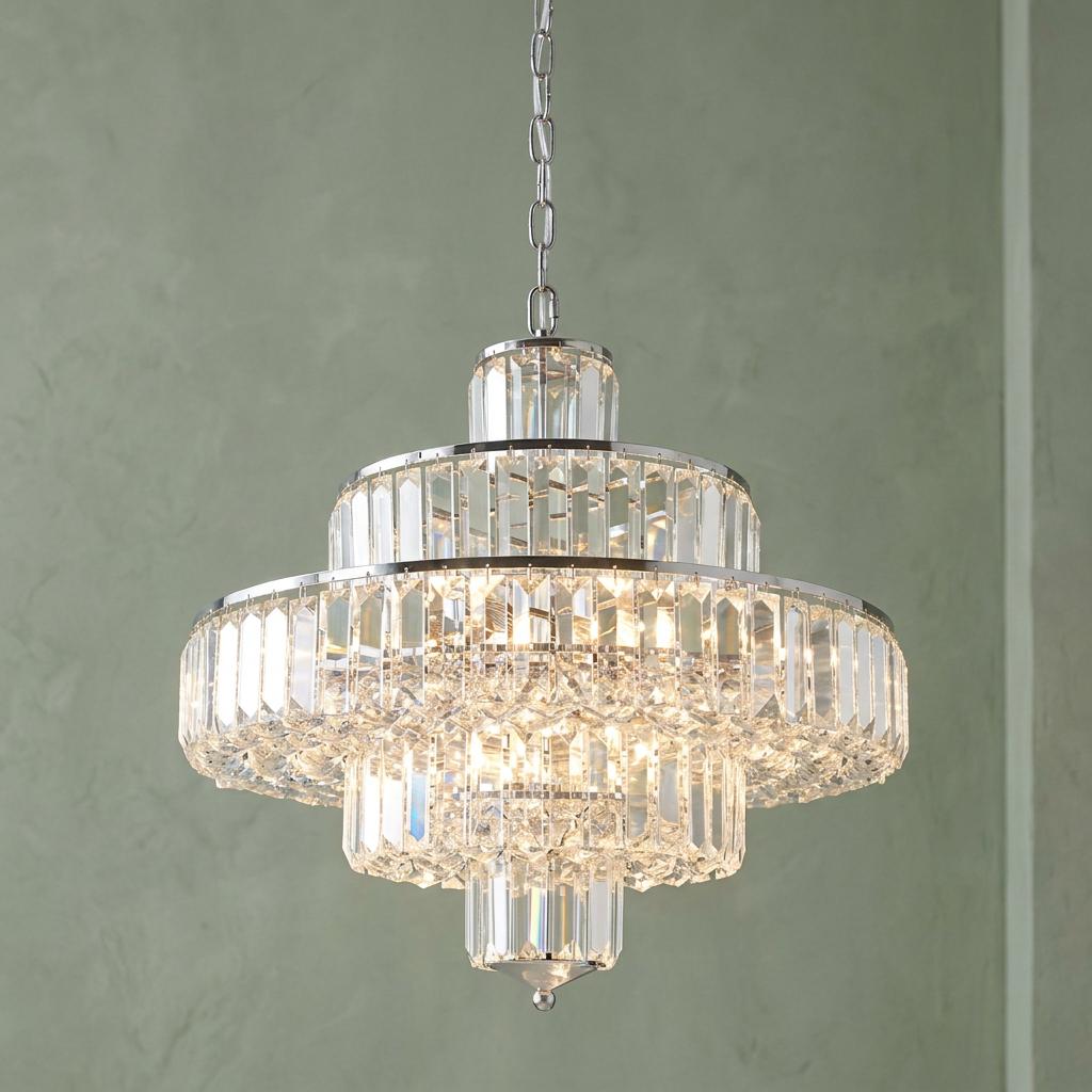A multi-tiered chrome and crystal pendant light with glowing prisms, hanging against a textured green wall.