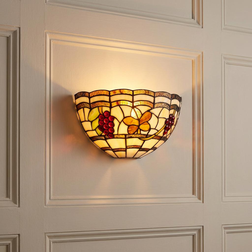 Illuminated Tiffany wall light featuring stained glass grapes and butterflies on a cream paneled wall.