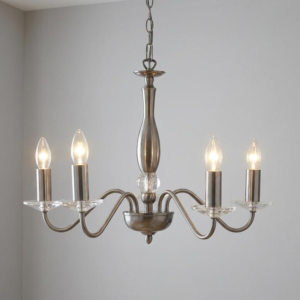 Five-light antique silver chandelier with curved arms and clear crystal bobeches against a neutral wall.