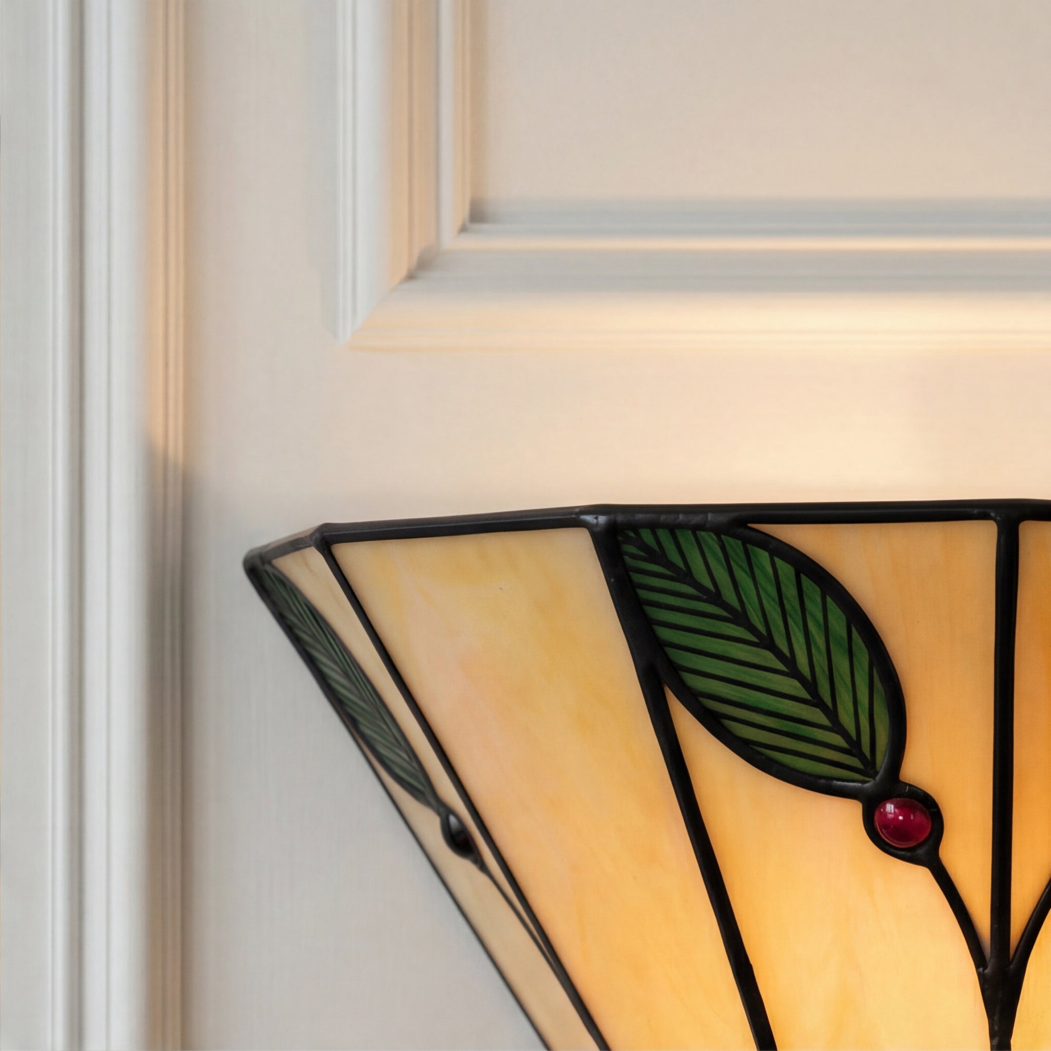 Stained glass panel with leaf design on a white wall