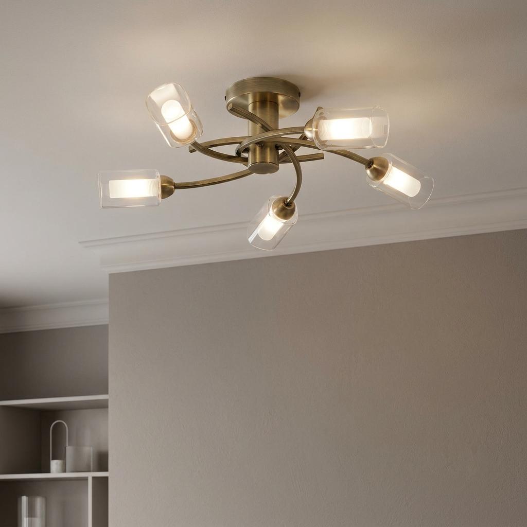 Antique brass flush ceiling light with five curved arms and clear glass cylinder shades.
