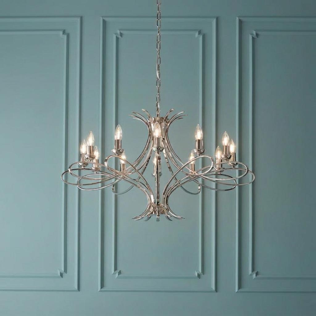 Twelve-light polished nickel chandelier with elegant sweeping arms hanging against a teal paneled wall.