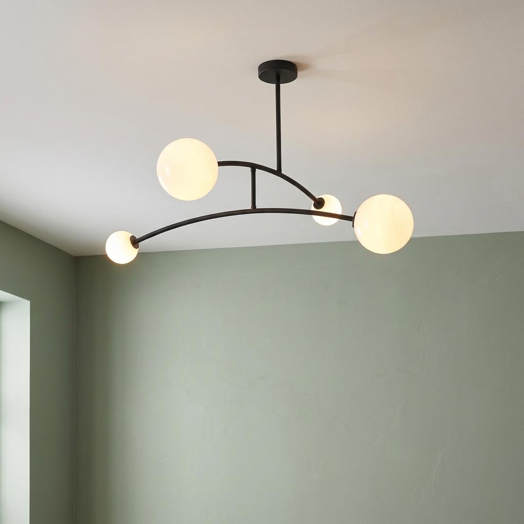 Four-light Art Deco semi-flush fixture with black curved arms and opal glass globes against a sage green wall.