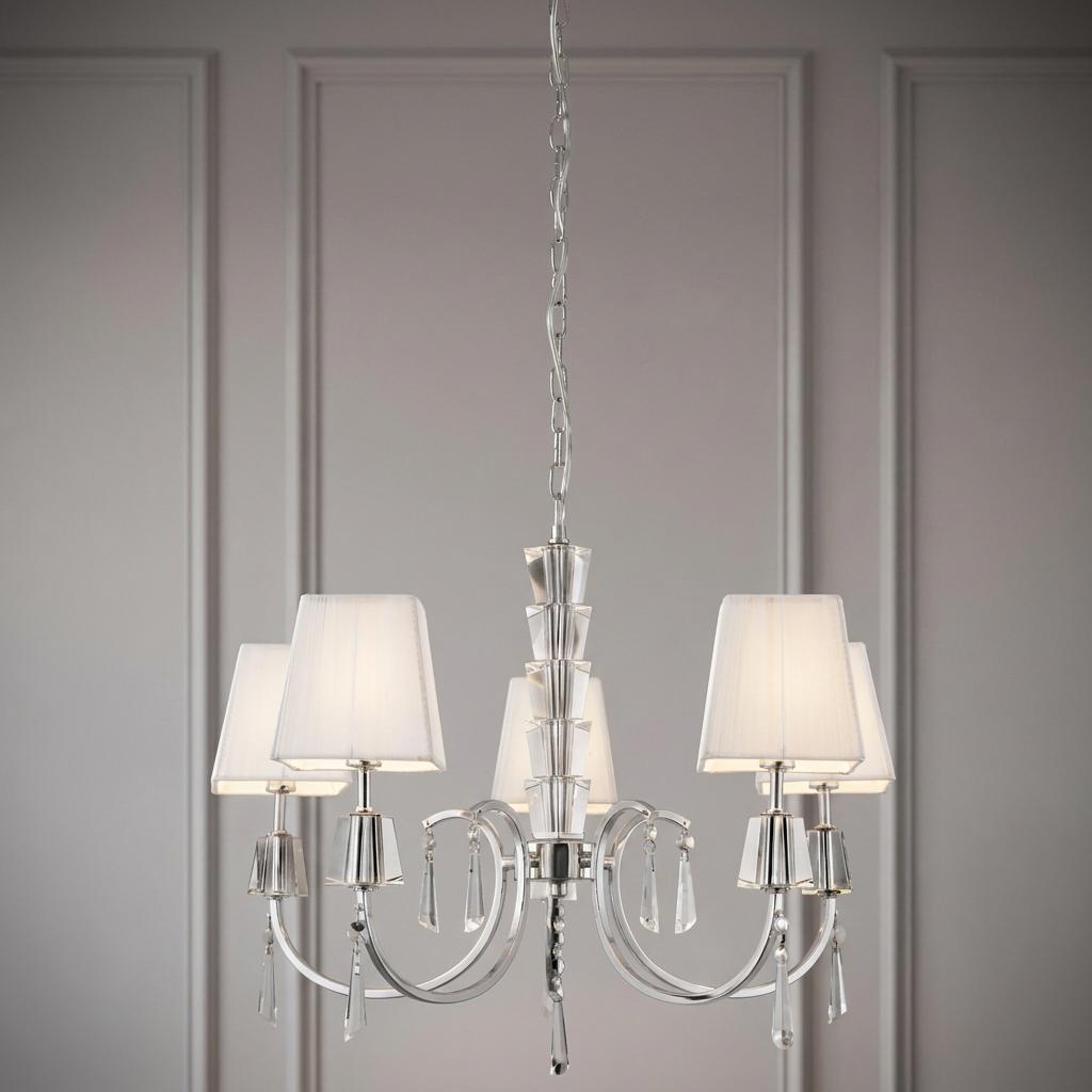 Chrome and crystal 5-light pendant with pleated white shades and droplets against a grey wall.