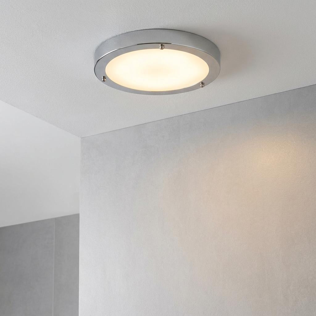 Portico chrome and frosted glass flush LED bathroom ceiling light glowing on a white ceiling.