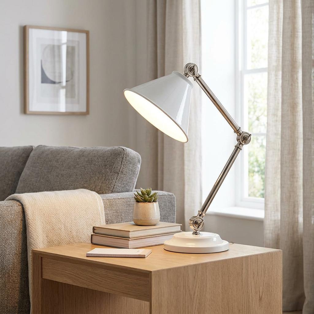 White and polished nickel task lamp with a conical shade on a wooden side table next to a sofa.