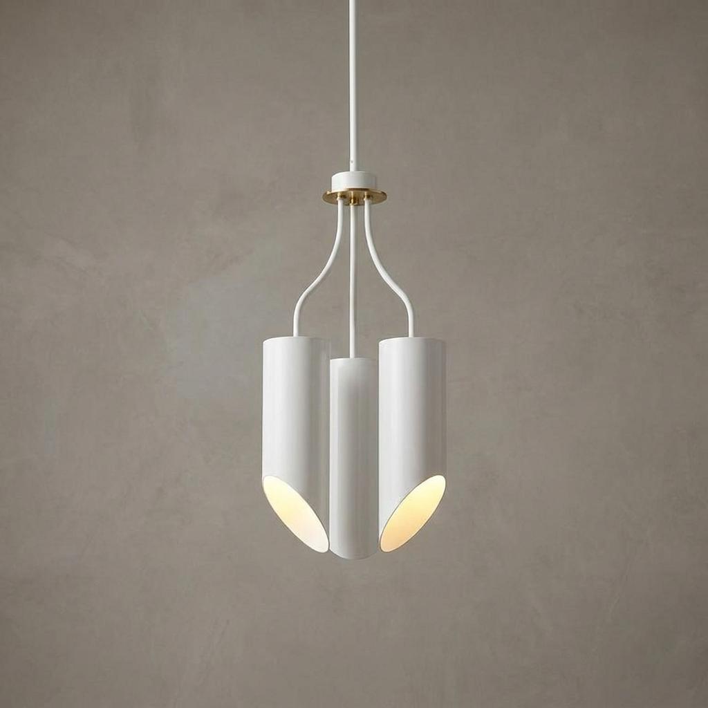 Modern three-light chandelier with white cylindrical shades and aged brass accents against a grey wall.