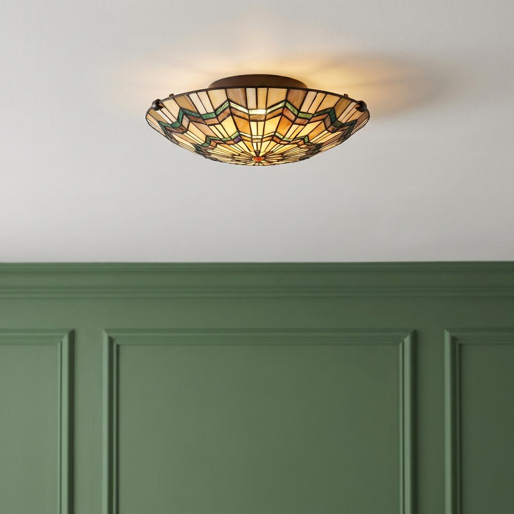 Quoizel Alcott Tiffany flush ceiling light with geometric stained glass shade glowing above green paneled walls.