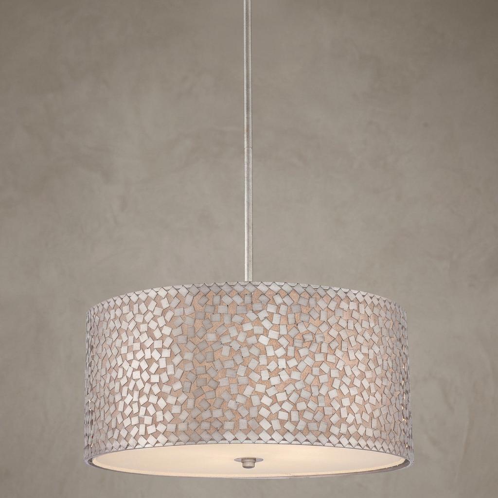 A large pendant light featuring a drum shade with a silver mosaic tile pattern against a neutral textured wall.