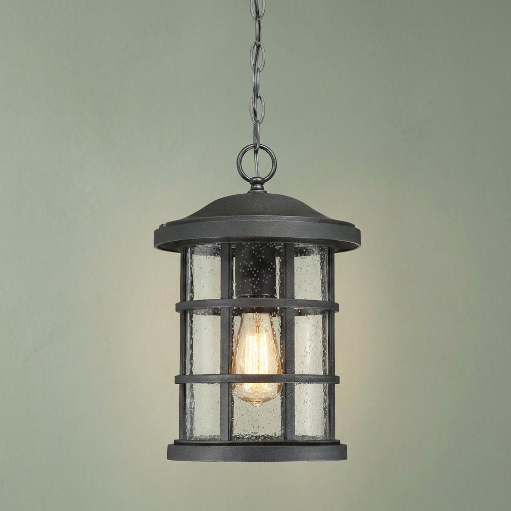 Quoizel Crusade 1 Light Black Chain Lantern with seeded glass and an Edison bulb against a green wall.
