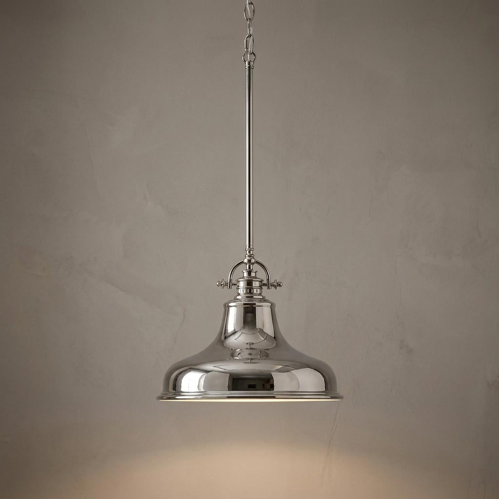 Polished imperial silver industrial pendant light hanging against a gray textured wall, illuminated from within.