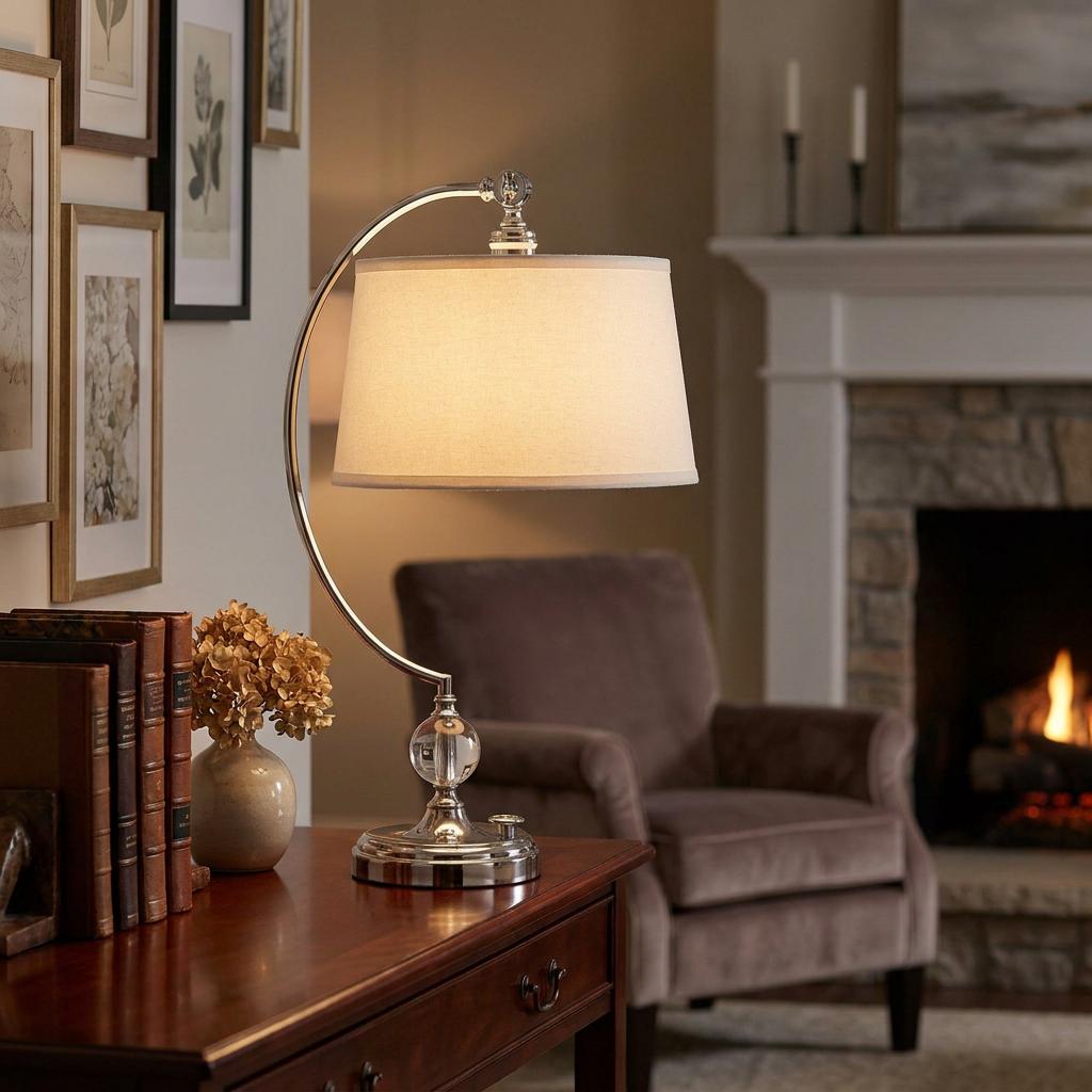 Quoizel Jenkins nickel table lamp with a cream shade and curved arm, lit on a desk in a cozy living room.