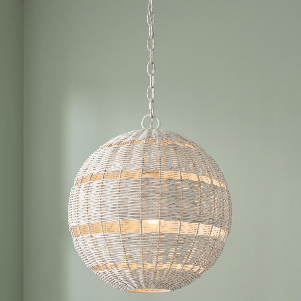 A spherical white woven wicker pendant light hangs from a chain against a light green wall.