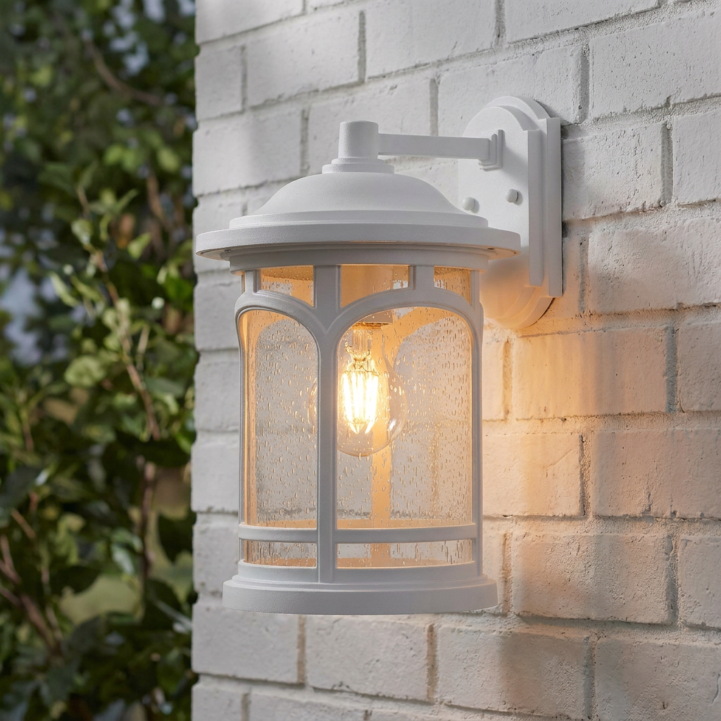 White lantern-style wall light with seeded glass and a warm bulb mounted on a white brick wall.