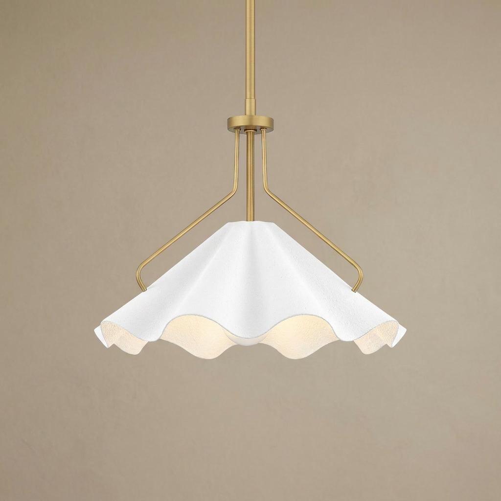 Modern brass ceiling pendant light with a decorative scalloped white textured shade against a plain wall.