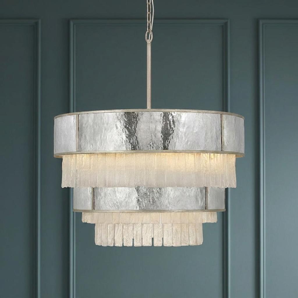Tiered pendant light with mercury glass and frosted glass fringes hanging against a dark teal paneled wall.