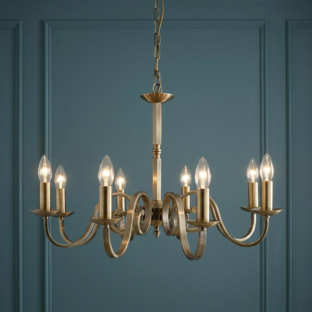Richmond 8-light antique brass chandelier with elegant scroll arms and candle bulbs against a teal panelled wall.