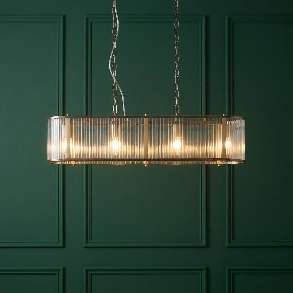 Ridgeton 4-light antique brass and ribbed glass linear pendant glowing against a dark green paneled wall.