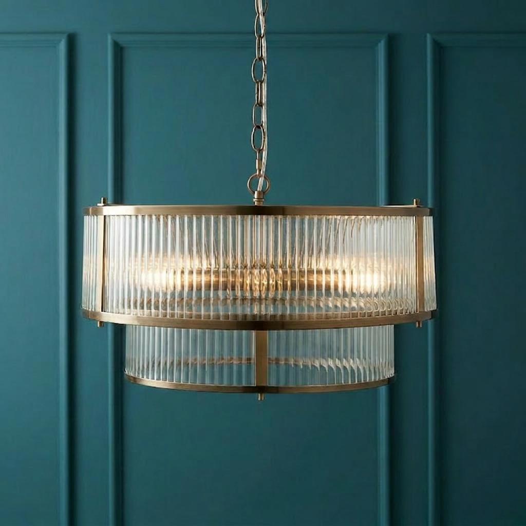 Two-tier antique brass and ribbed glass pendant light hanging against a dark teal paneled wall.