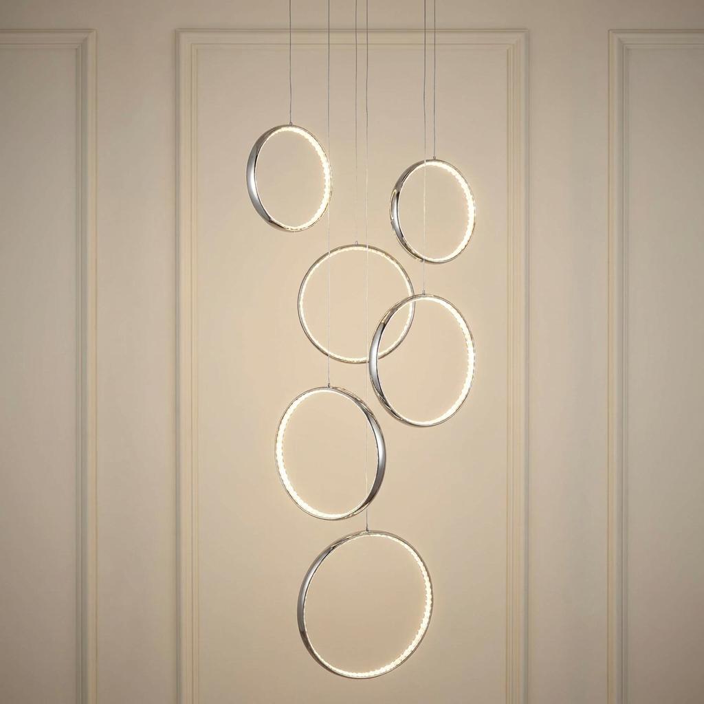 Six cascading chrome and crystal LED rings hang as a multi-drop pendant against a paneled neutral wall.