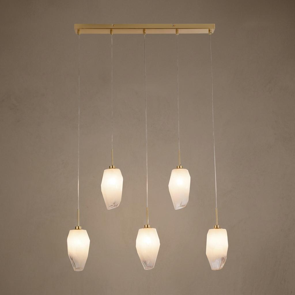Five-light satin brass bar pendant with rocky white glass shades hanging at staggered heights.