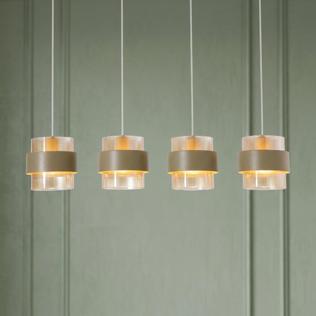 Four amber ribbed glass pendant lights with sand metal bands hanging against a green paneled wall.