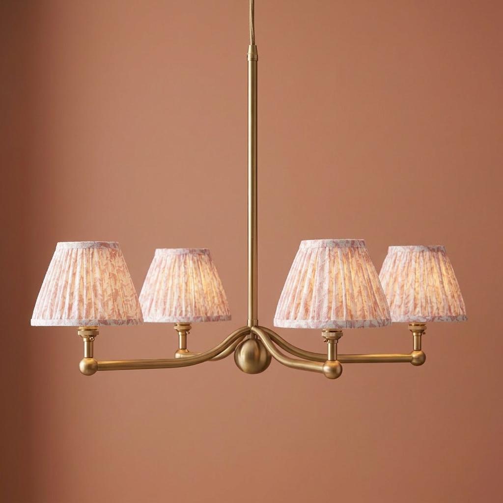 Santiago brass four-light pendant with pleated peachy leaf shades against a terracotta wall.