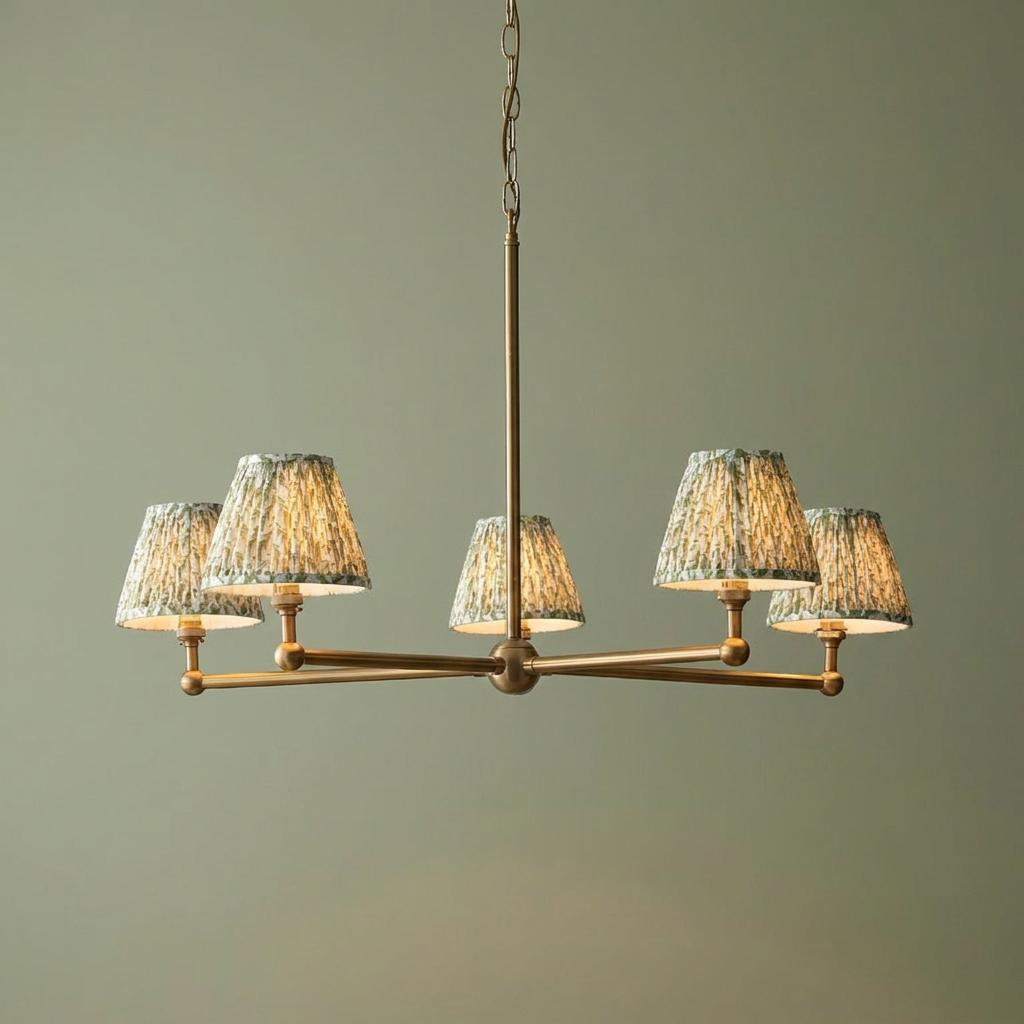 Santiago brass 5-light pendant ceiling light with green leaf patterned pleated shades against a green wall.