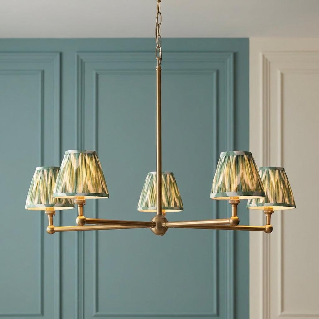 Santiago brass 5-light pendant chandelier with green zigzag shades against a teal paneled wall background.