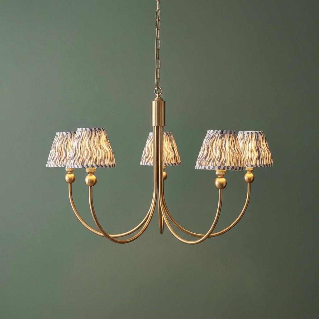 Five-arm brass chandelier with grey ripple patterned shades against a green background.