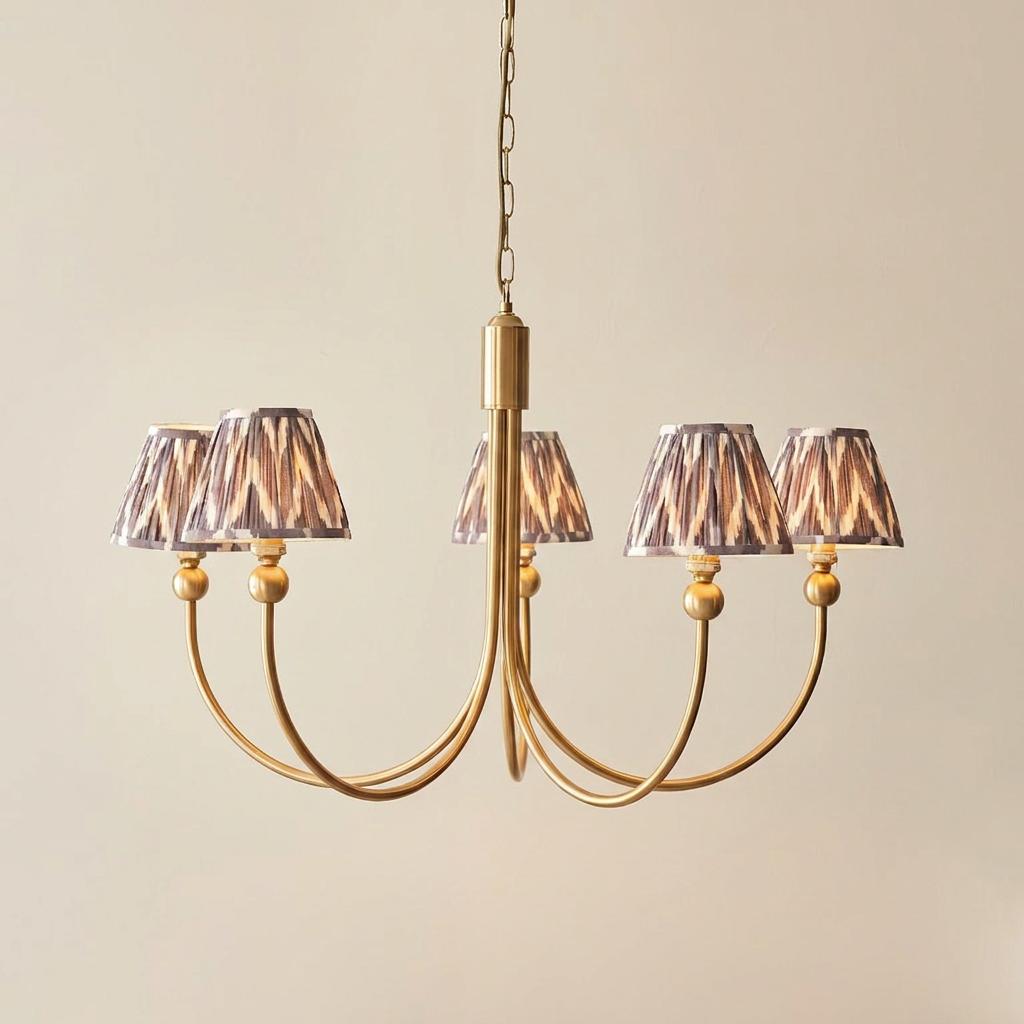 Santiago brass chandelier with five curved arms and grey zigzag patterned shades against a plain wall.