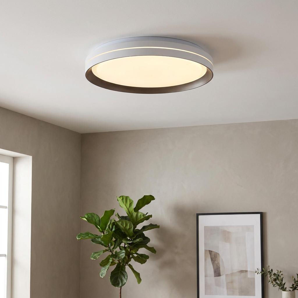 Modern latte and white saucer LED ceiling light glowing in a minimalist room with a green plant and framed art.