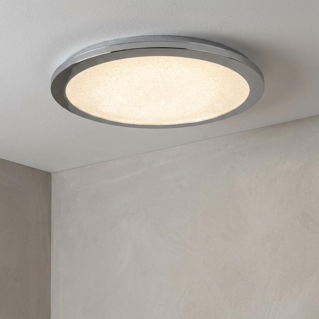 Circular LED flush ceiling light with a chrome rim and textured crystal sand diffuser illuminated on a white ceiling.
