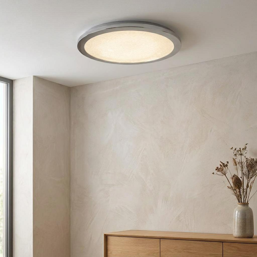 Circular LED flush ceiling light with chrome rim and crystal sand diffuser illuminating a modern interior.