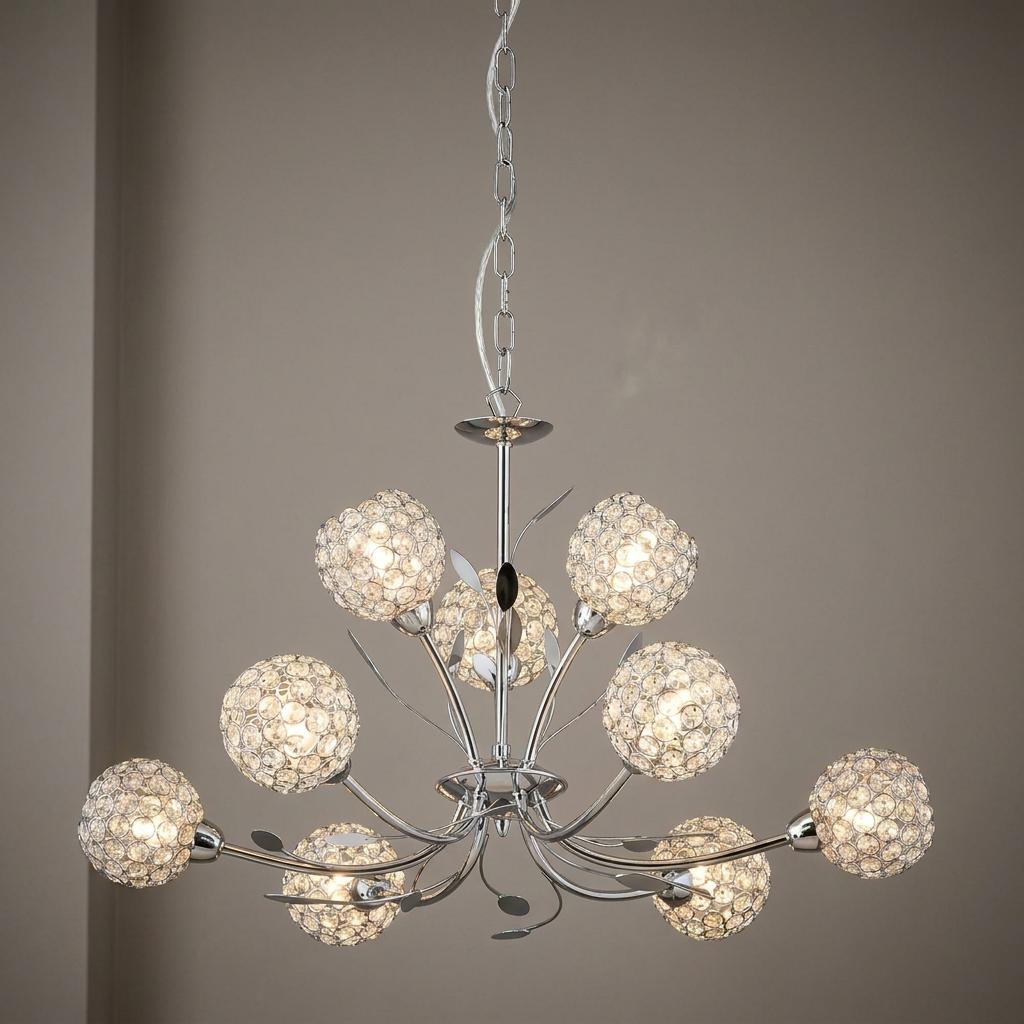 A nine-light chrome chandelier with spherical glass crystal shades and decorative metal leaves against a neutral wall.