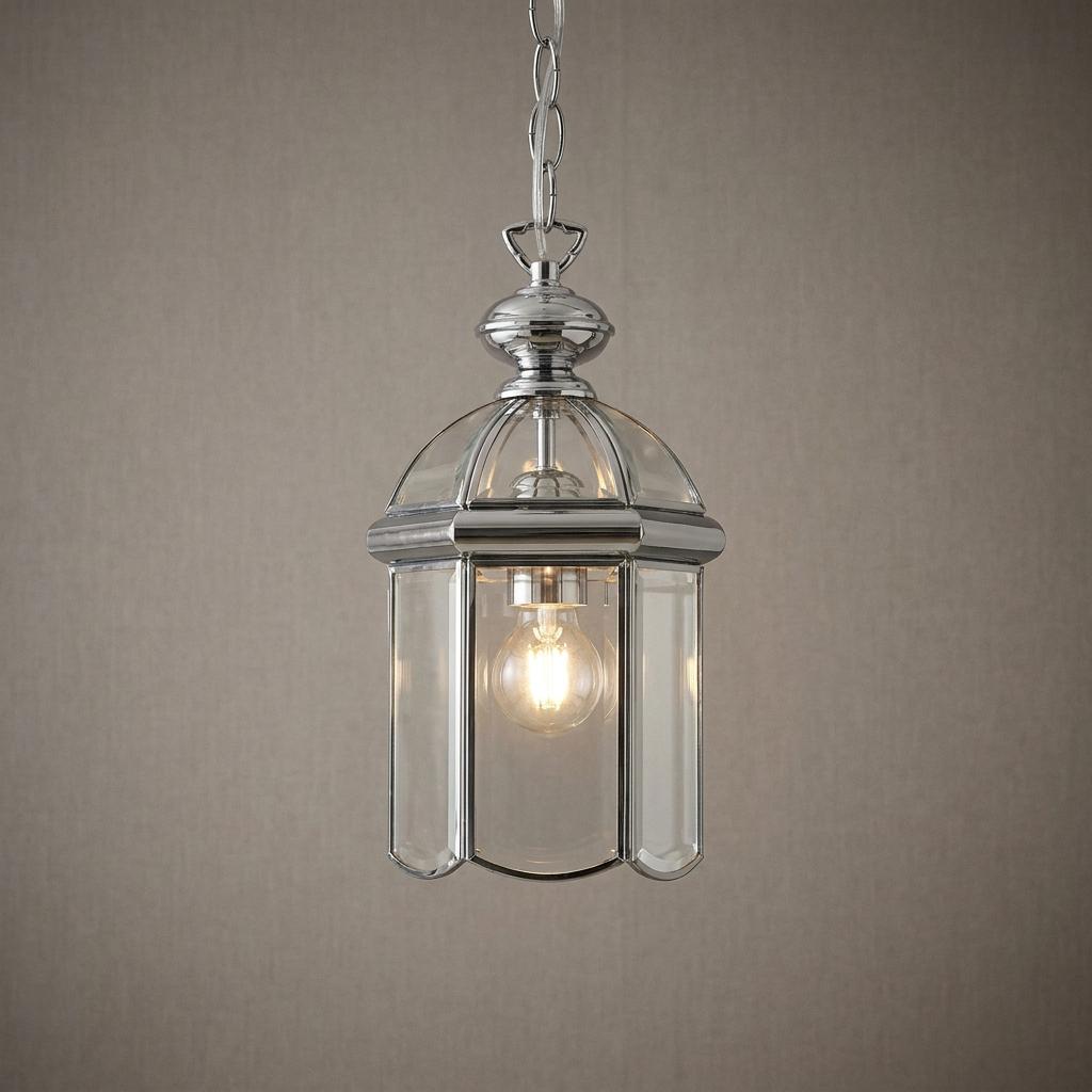 Chrome domed lantern pendant light with bevelled glass panels hanging against a textured grey wall.