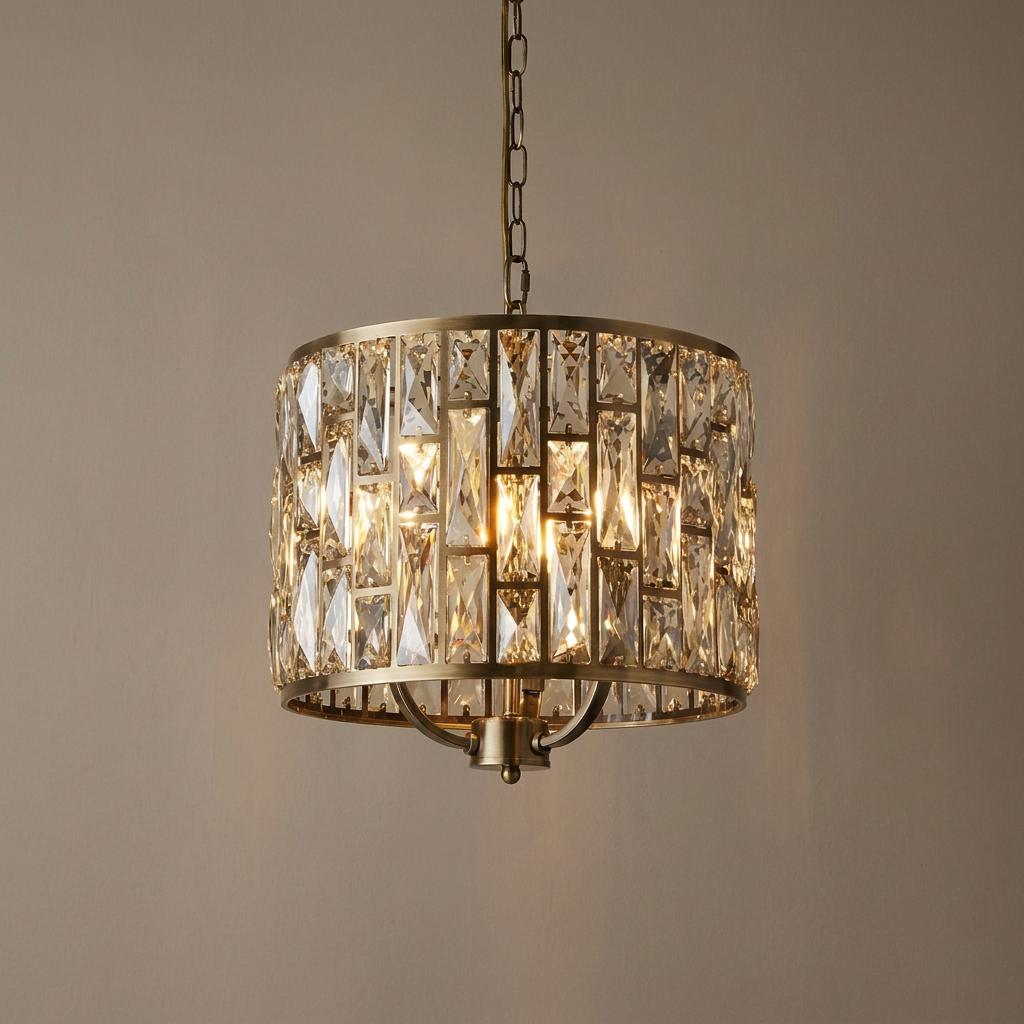 Elegant brass drum pendant light with sparkling rectangular glass prisms, illuminated against a neutral background.