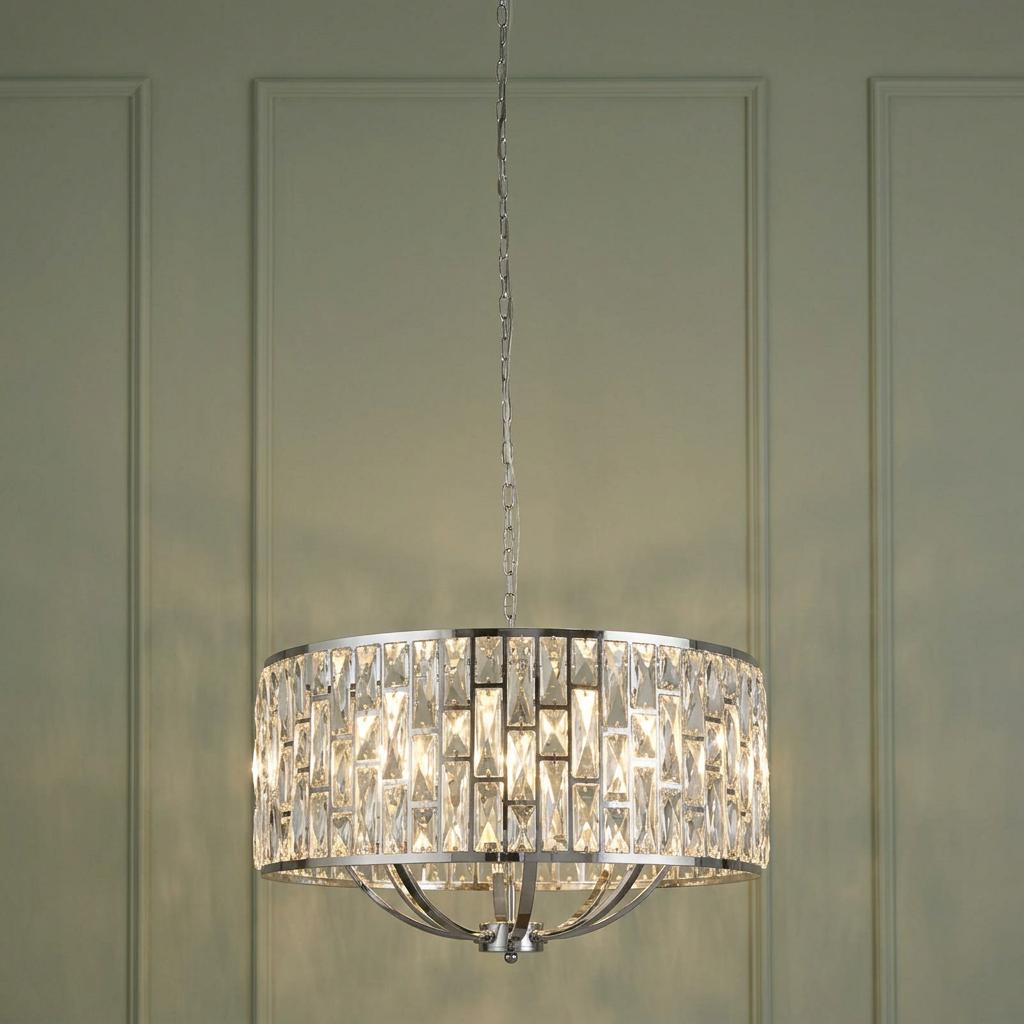 An 8-light chrome drum pendant with rectangular crystal glass panels, hanging against a sage green paneled wall.