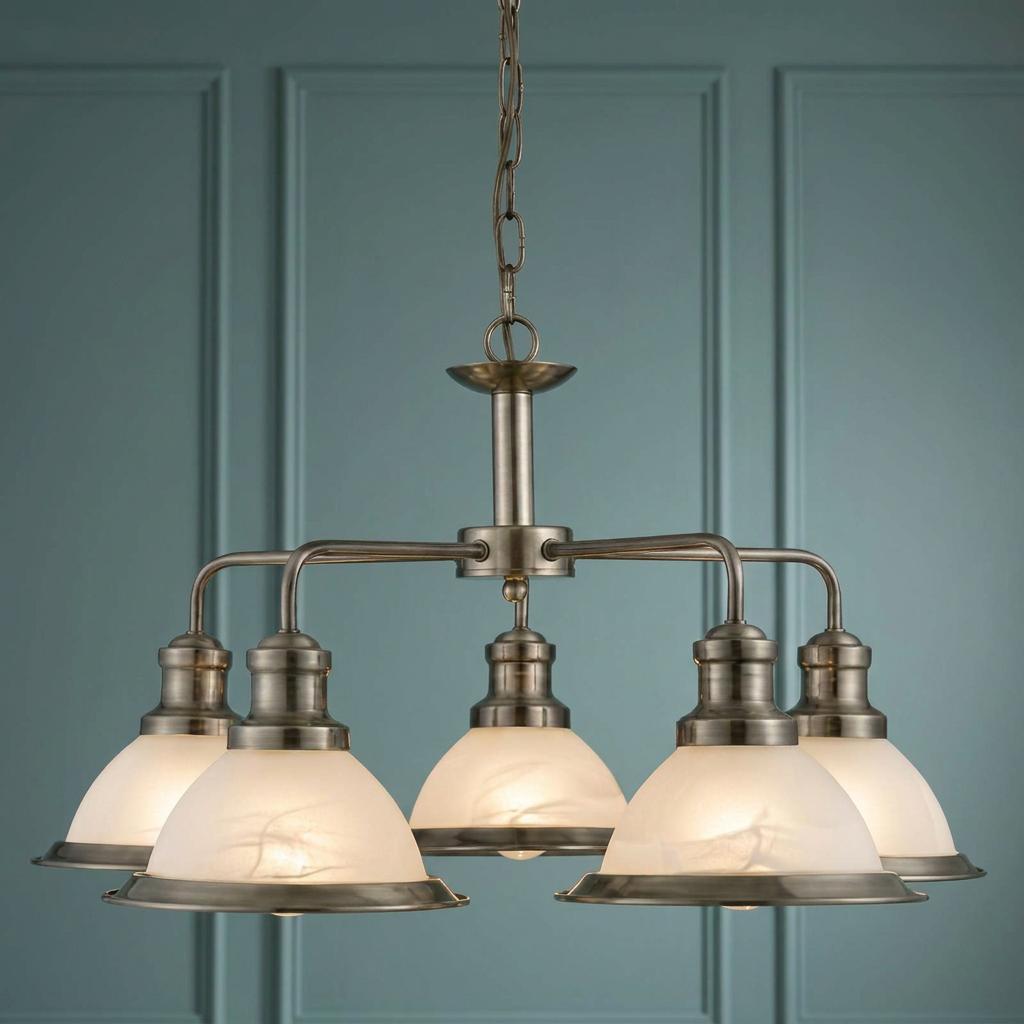 Antique brass five-light ceiling pendant with white marble-effect glass shades against a teal panelled wall.