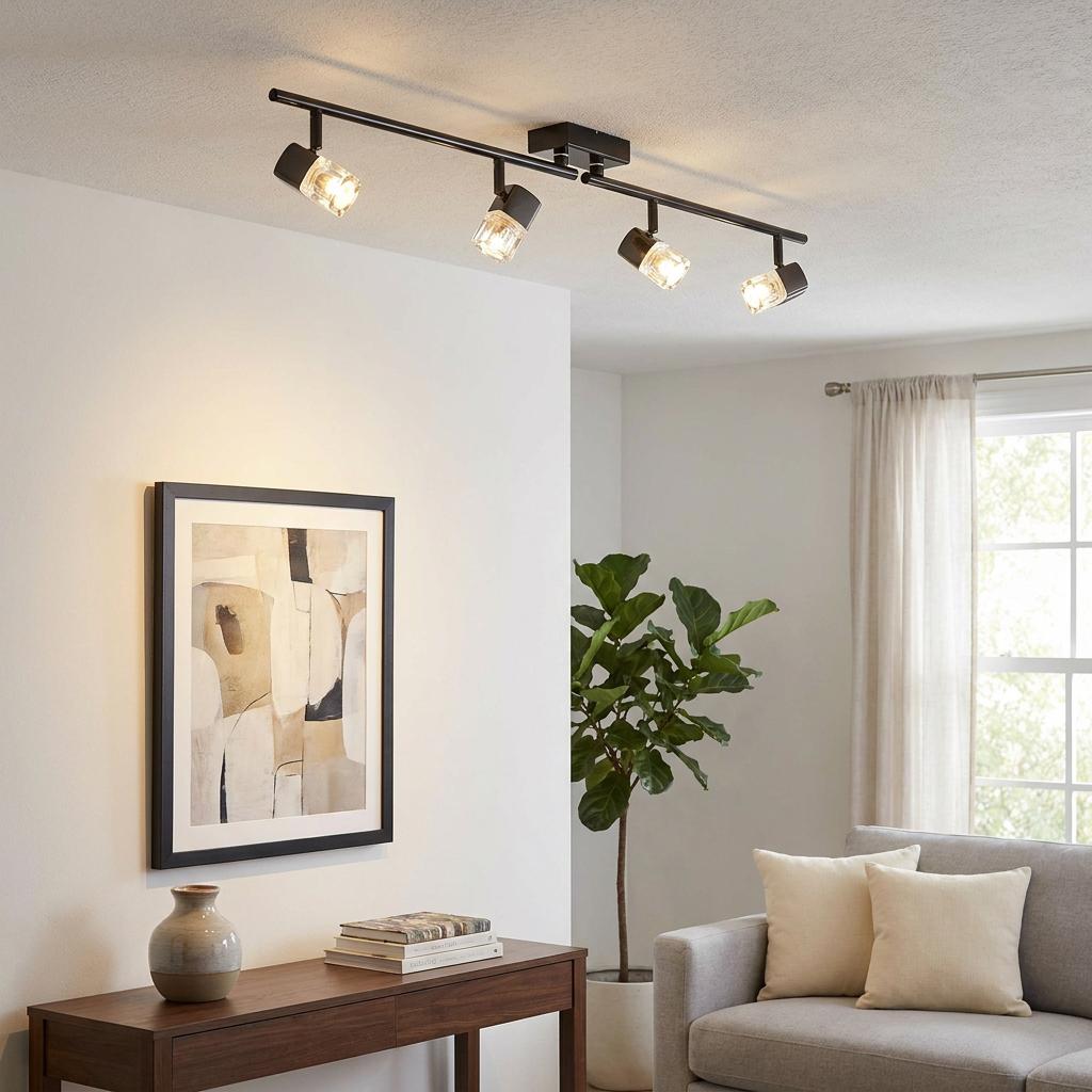 Four-light black split bar spotlight with glass shades illuminating a modern living room setting.