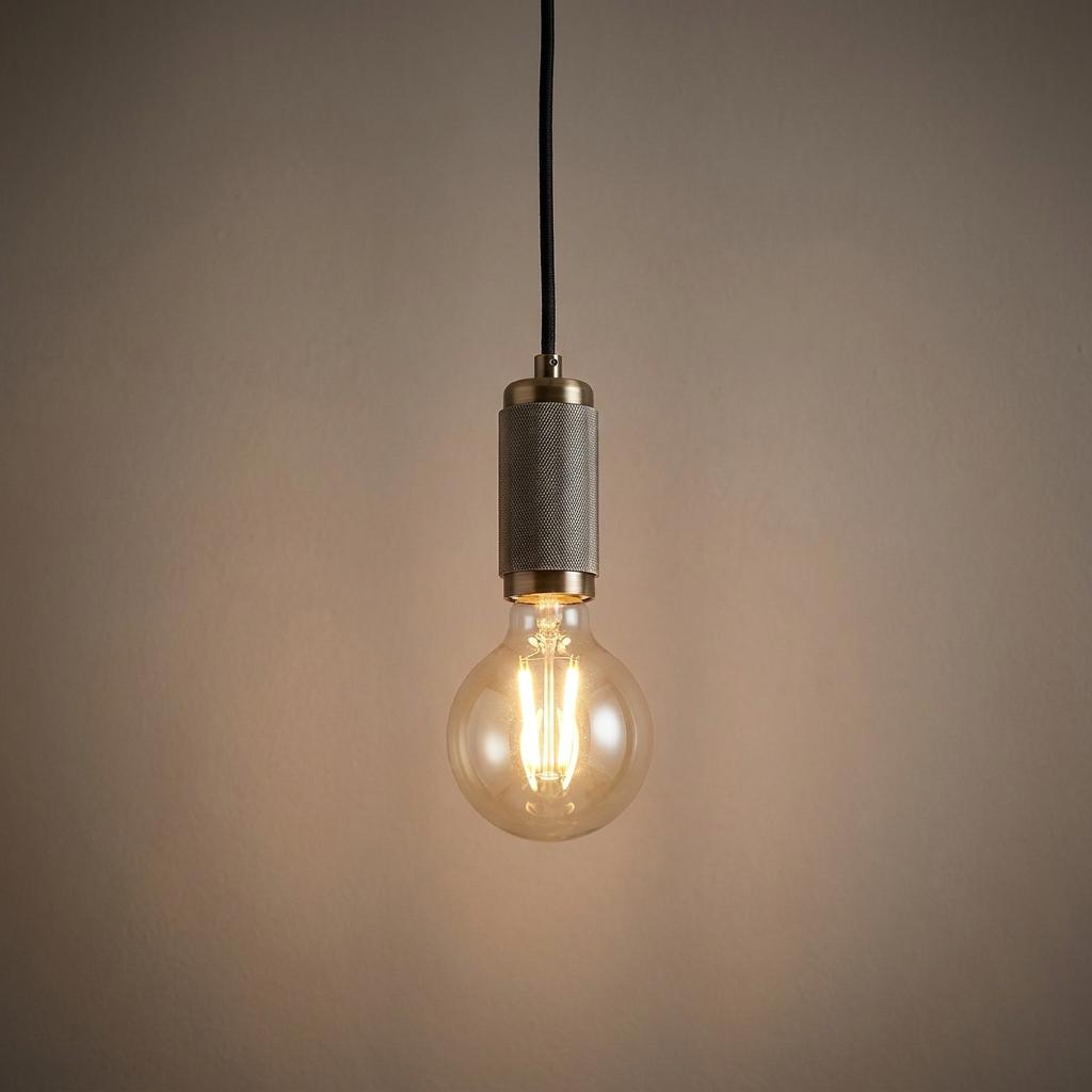 Industrial brass pendant light with a knurled socket and glowing LED filament globe bulb.