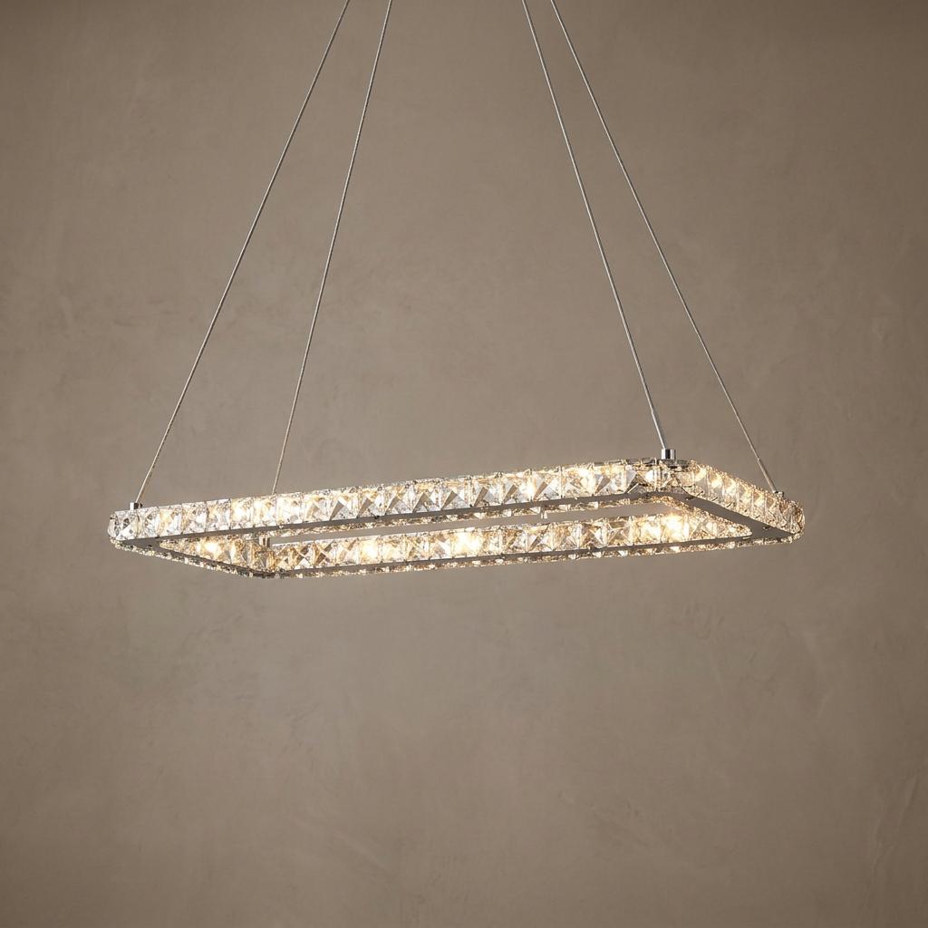 Rectangular chrome and crystal LED pendant light suspended by thin cables against a neutral wall.