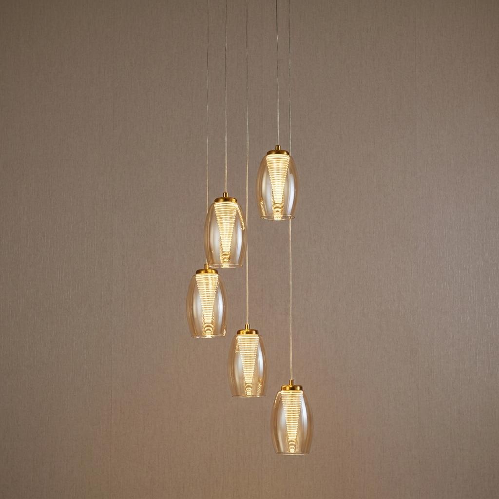 Searchlight Cyclone five-light LED pendant featuring spiraled glass shades in champagne against a neutral wall.